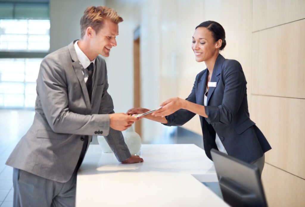 Person traveling for business reviewing hotel benefits and amenities with front desk agent. 