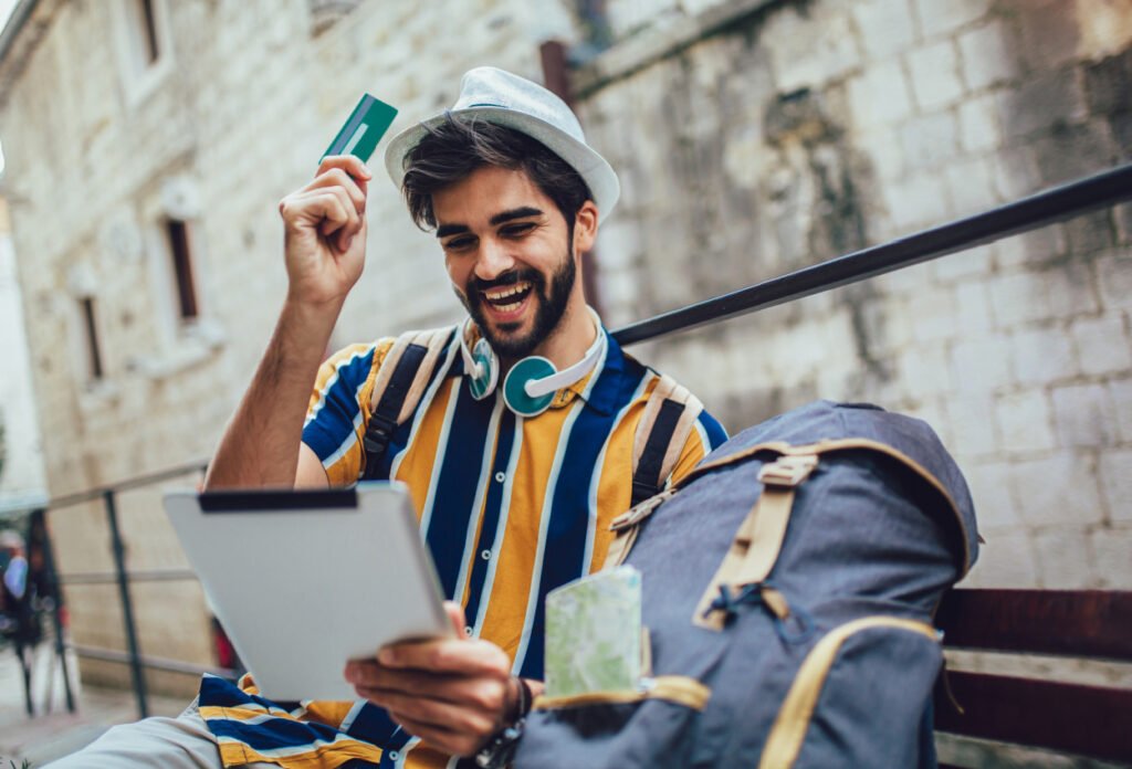 Young tourist man buying online with a credit card and a tablet in the street